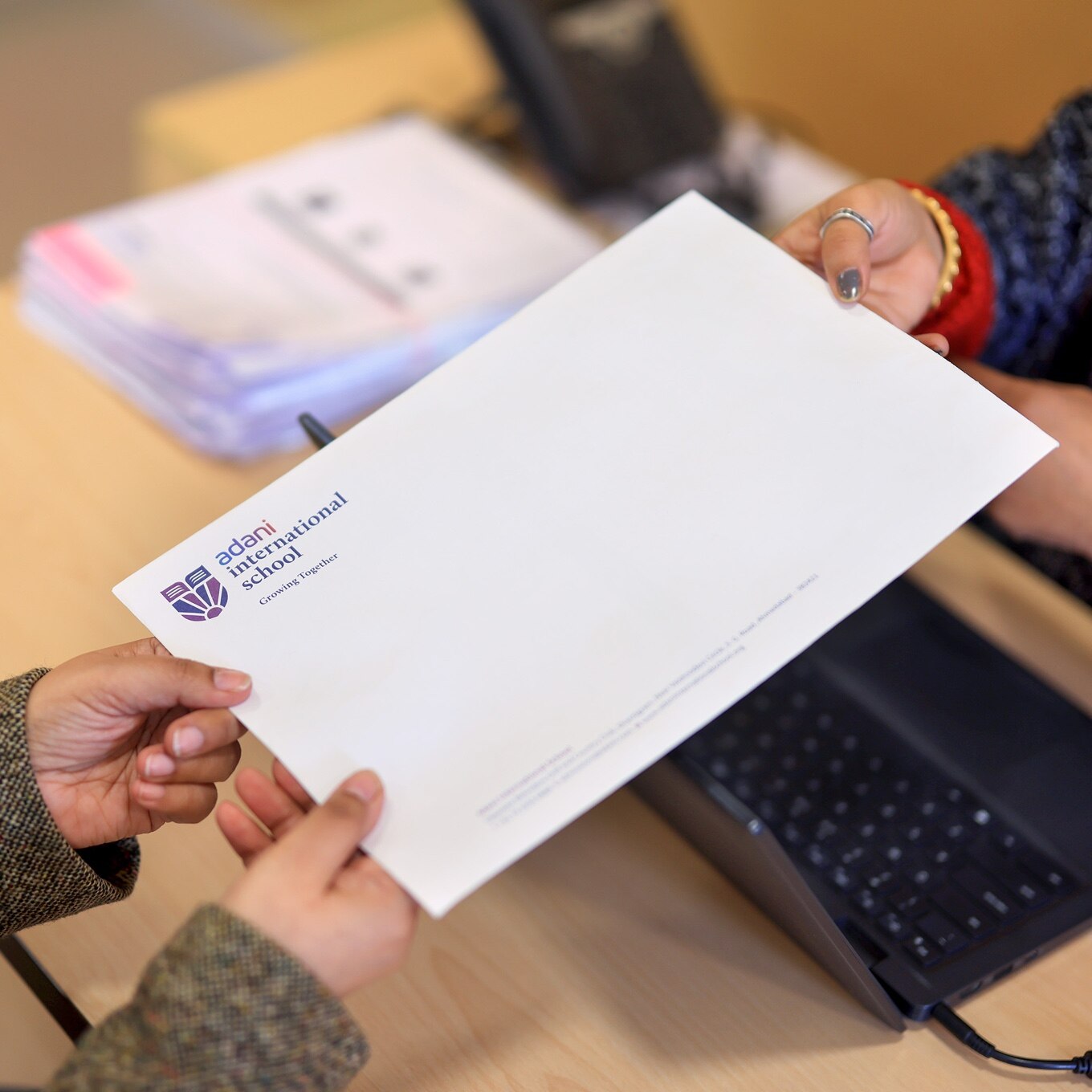 teacher giving envelope to student at Adani international School