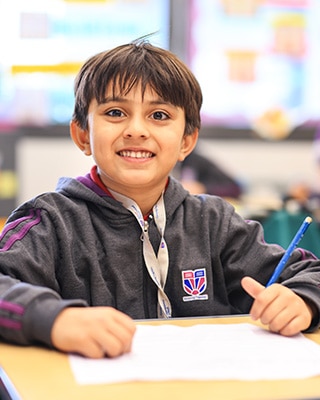 a primary student writing on notebook at Adani International School