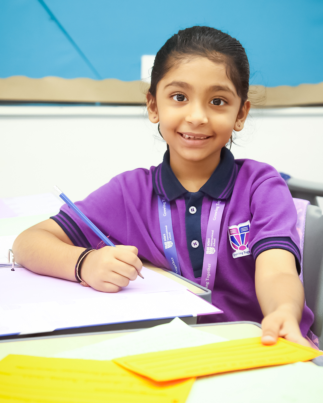 a primary student writing on notebook at Adani International School
