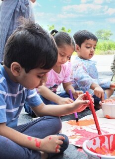 students painting a cardboard at Adani international School