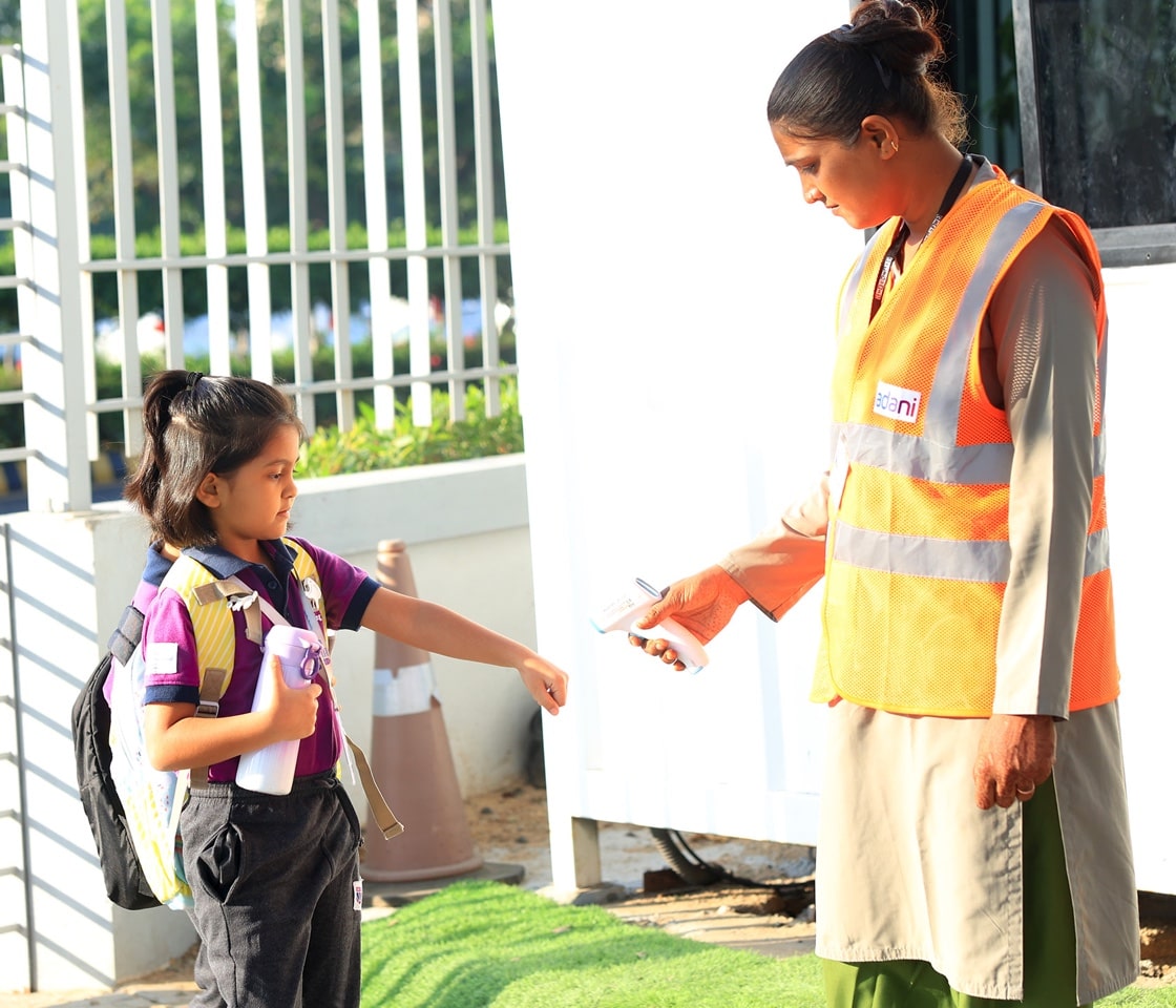 security perssonel checking temperature of a student at adani international school